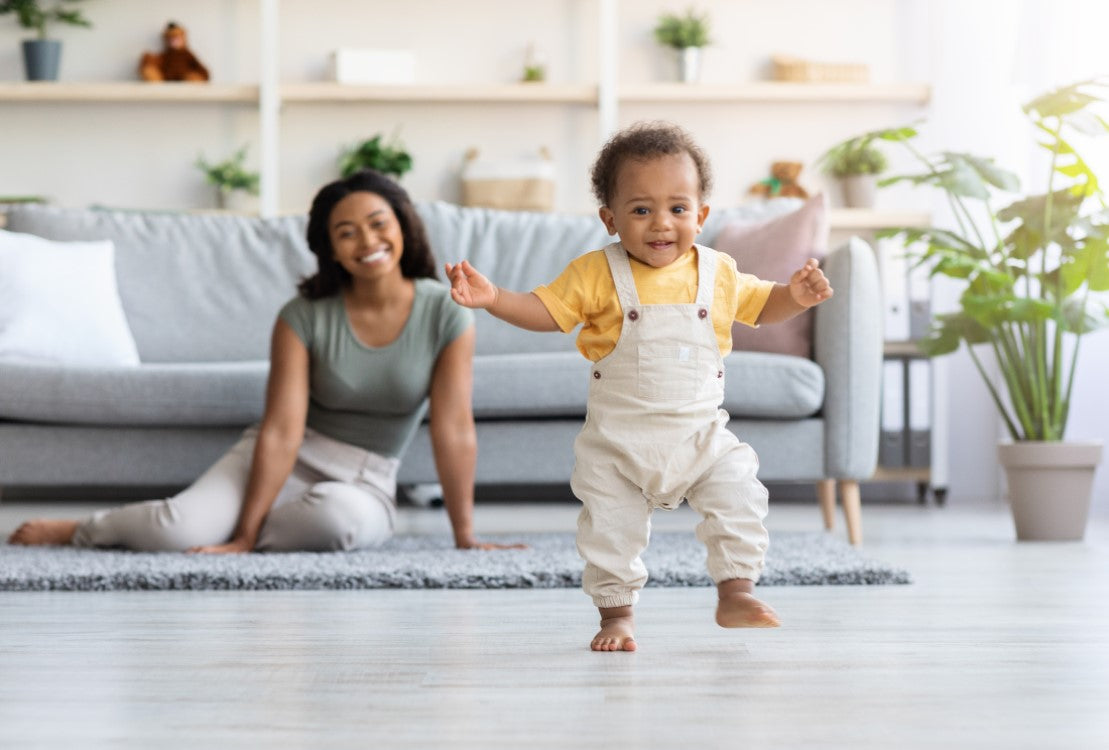 A mother watching a barefoot baby walk across a floor that was cleaned using PermaSafe products, demonstrating that PermaSafe products are safe to use around people, pets, and even babies.