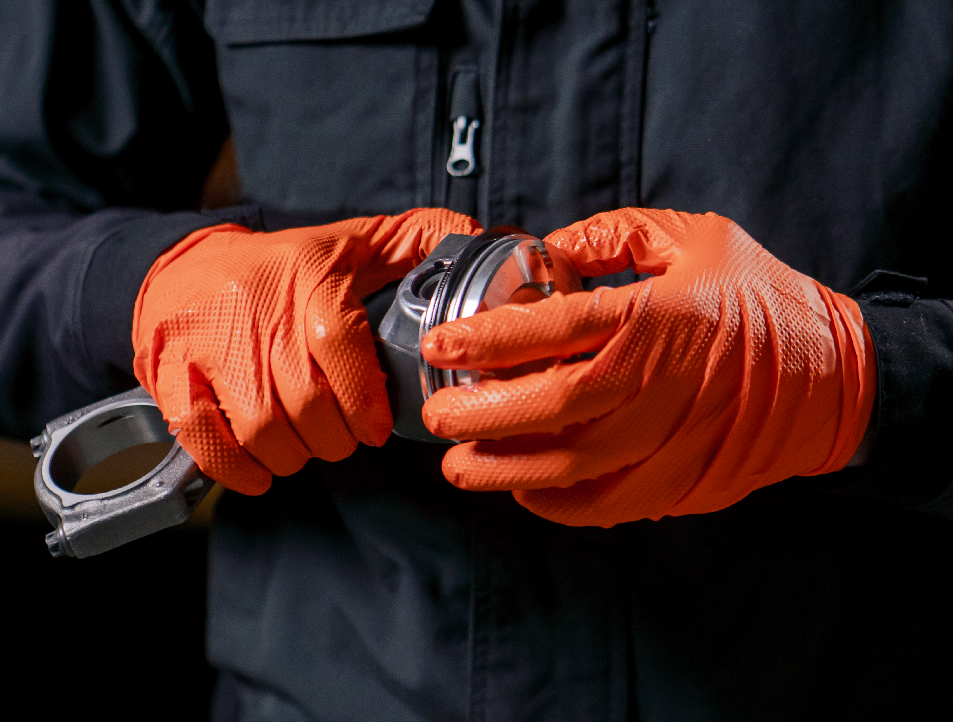 Hands wearing PermaSafe industrial strength orange and black gloves