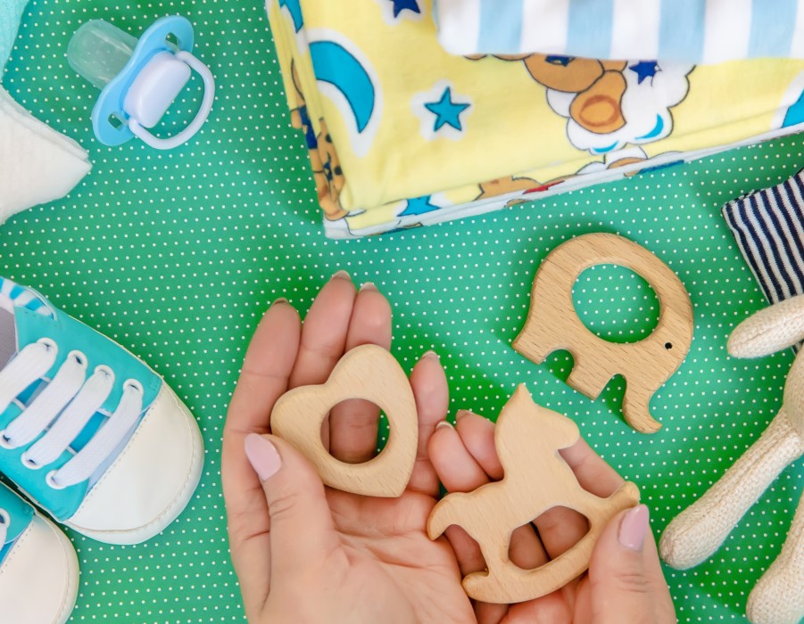 Someone holding baby toys and accessories demonstrating that PermaSafe products are effective on soft porous surfaces such as fabric, rubber, plastic, and wood whereas most other antimicrobial products are only effective on hard non-porous surfaces.