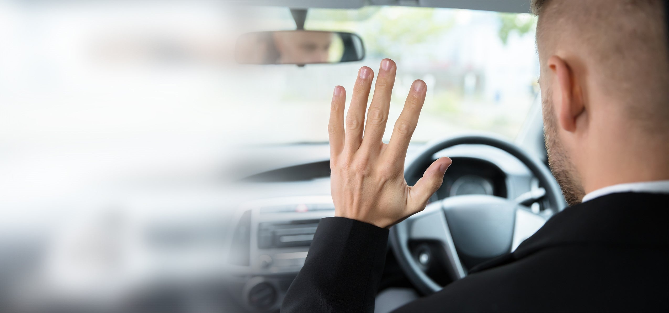 driver inside a car that is not touching the steering wheel but could have if he had used the permasafe Complete Vehicle Disinfection and Long Term Antimicrobial Protection products