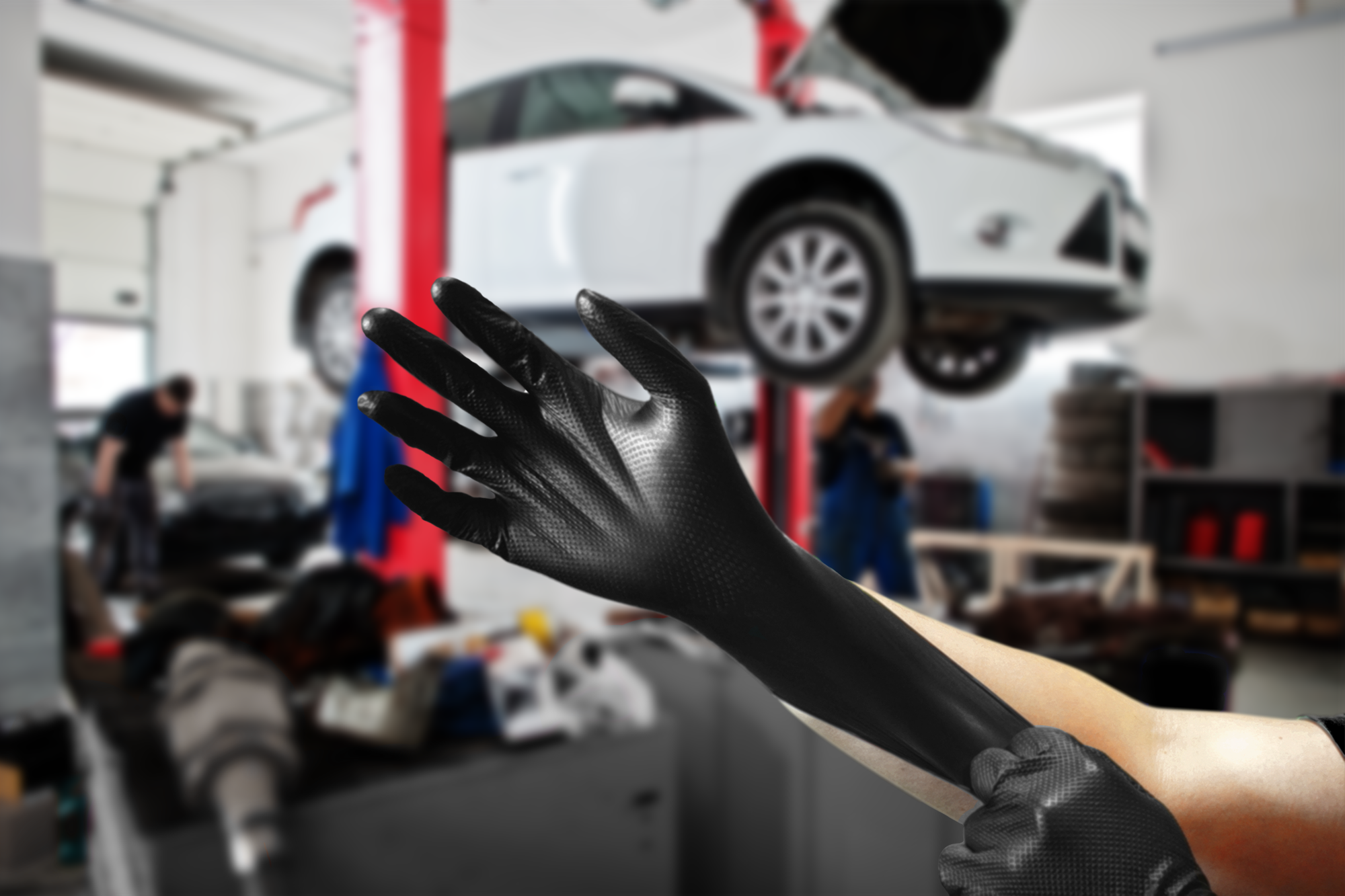 a mechanic in an auto repair shop pulling on a pair of permasafe industrial strength nitrile gloves because they offer the best protection and durability while doing challenging tasks