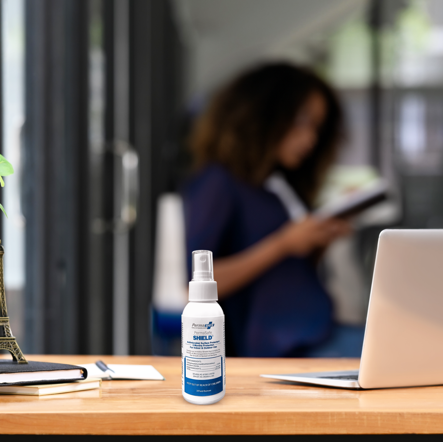 convenient 3 ounce spray bottle of permasafe shield, our 90 Day, All-Purpose, Antimicrobial Surface Protectant sitting on an office desktop highlighting how it may be applied while on the go to protect you from all the surfaces you come into contact with.